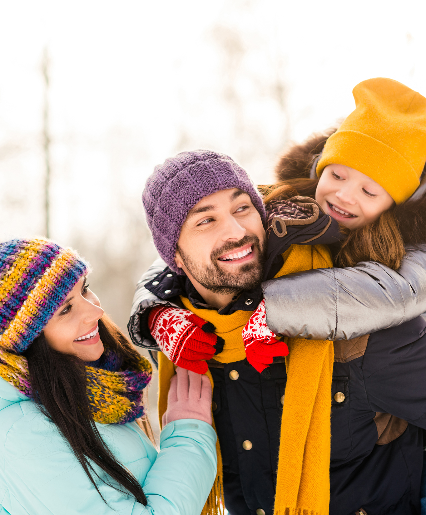 mother, father, and child outside playing in the snow