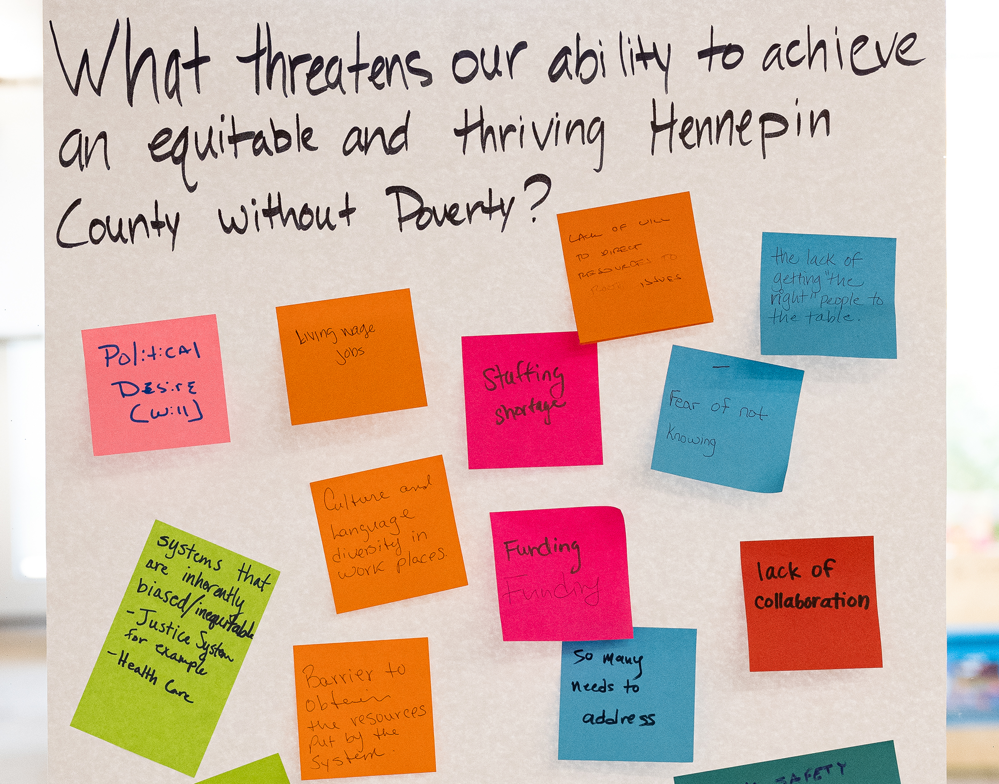 post-it notes answering "what threatens our ability to achieve an equitable and thriving Hennepin County without poverty?"