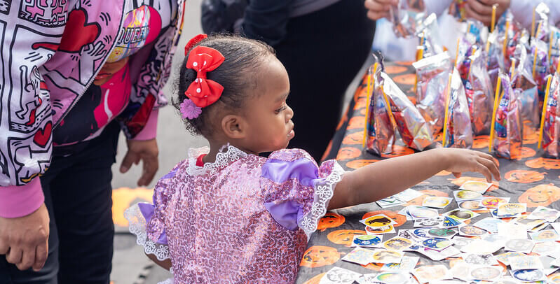 Spooktacular_Photo-e1734713778923 elementary-aged girl in a sparkly costume picks out Halloween stickers