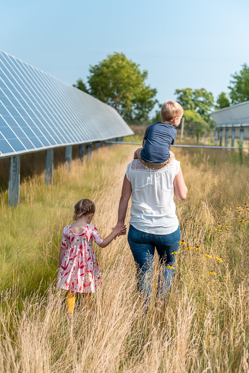 Mother walking through a solar garden with her two children 