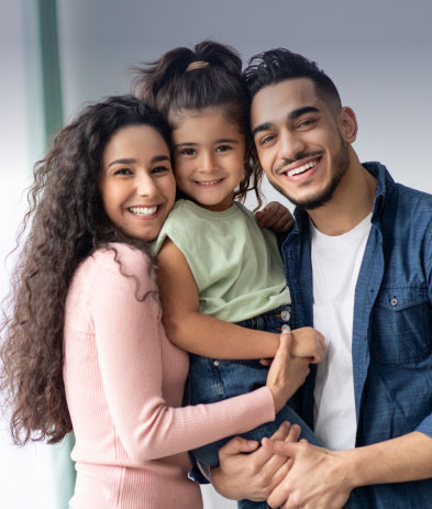 Mother, child, and father huddled together in a group hug smiling