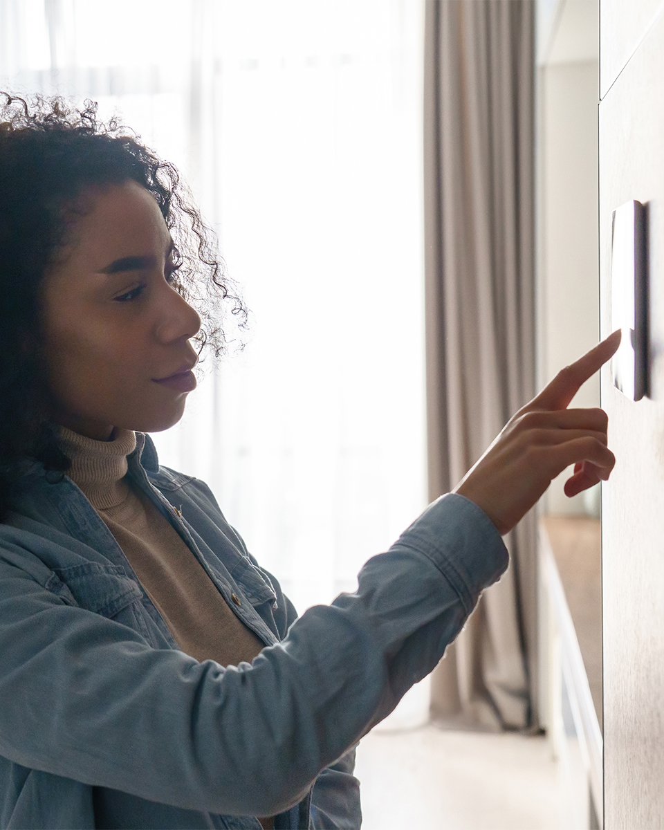 Woman adjusting the thermostat in her home