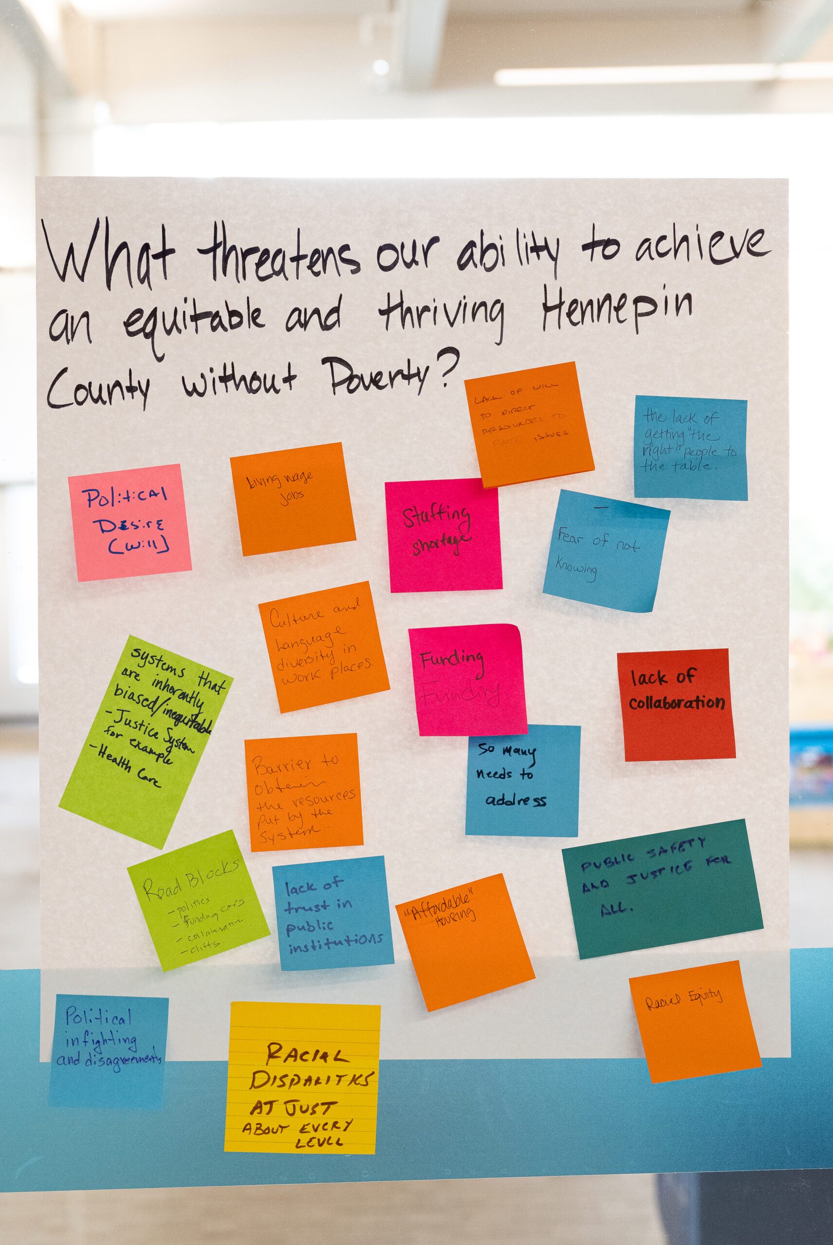 post-it notes answering "what threatens our ability to achieve an equitable and thriving Hennepin County without poverty?"