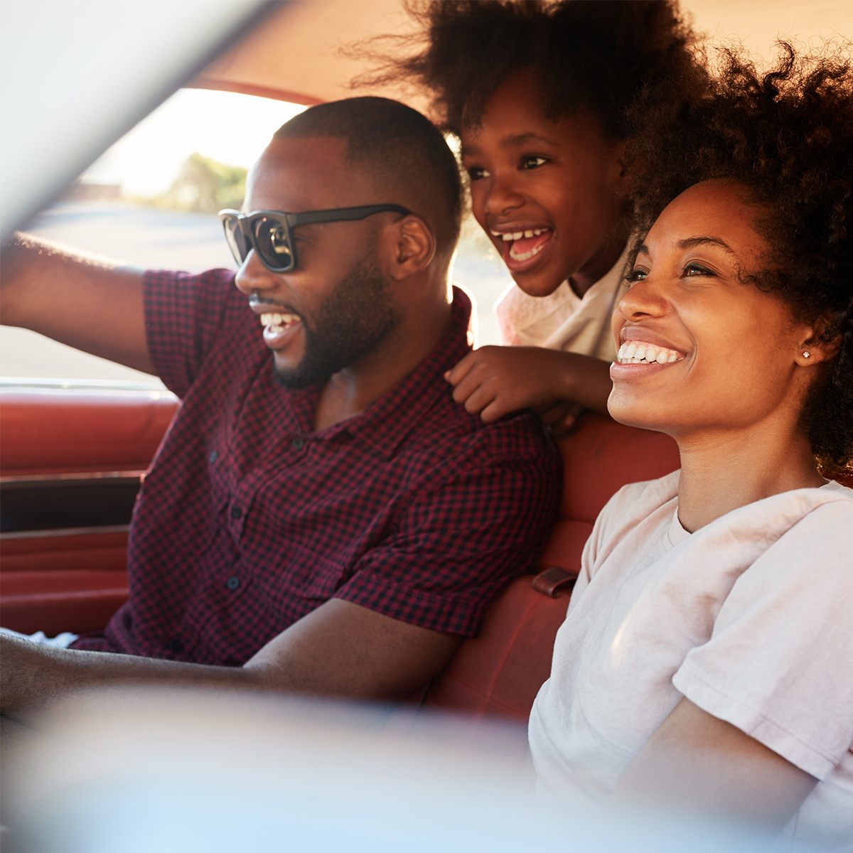 father, elementary-aged daughter, and wife driving in the car