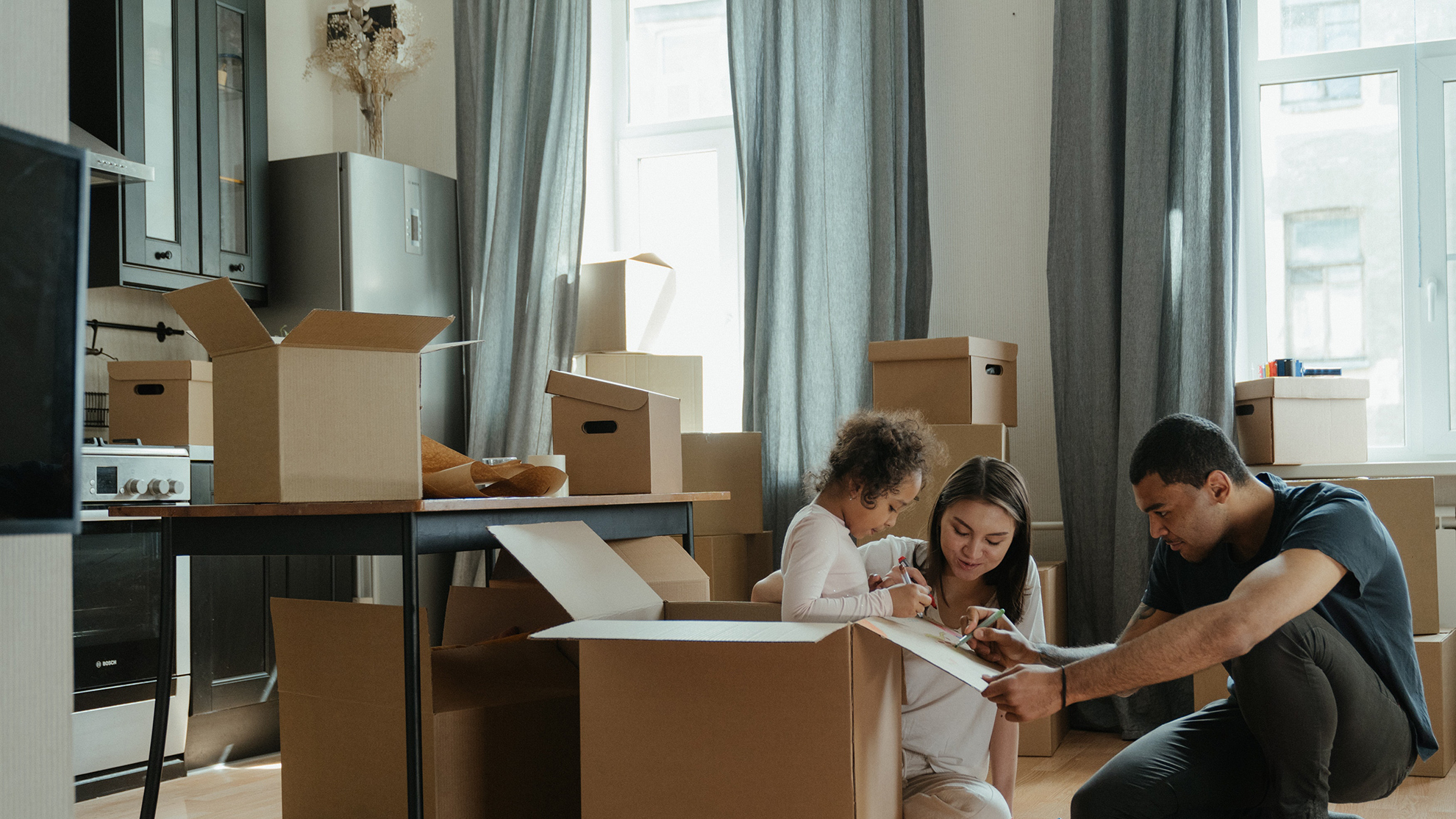 child, mother, and father packing boxes in their apartment