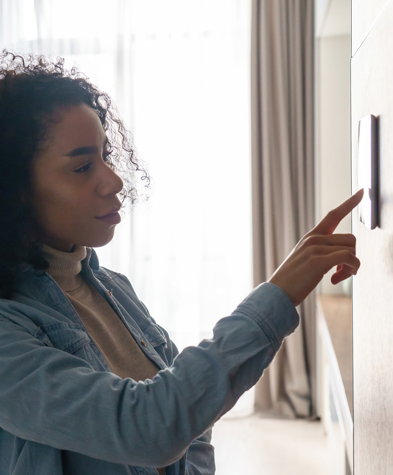 Woman adjusting the thermostat in her home