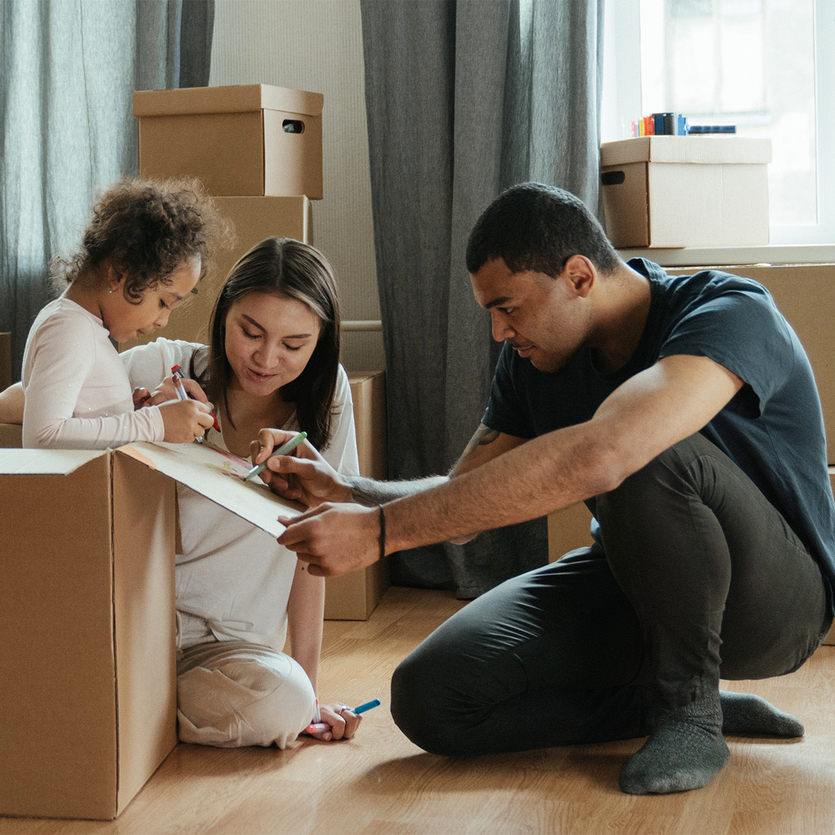 child, mother, and father packing boxes in their apartment