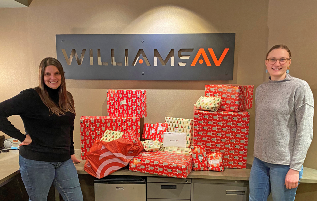 Williams AV staff member and CAP-HC staff member with wrapped Winter Family Sponsorship gifts