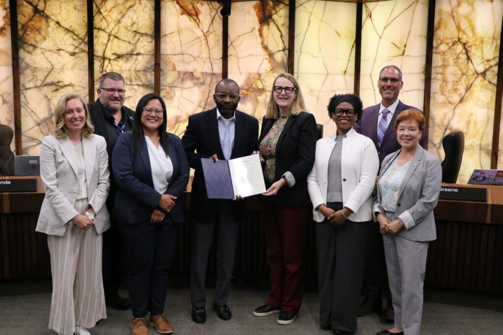 Community Action Month Proclamation presented at Hennepin County Board of Commissioners meeting on May 19, 2026. Pictured left to right: Hennepin County Commissioners Heather Edelson, Jeffrey Lunde, and Irene Fernando; Dr. Clarence Hightower, Executive Director at Community Action Partnership of Hennepin County; Hennepin County Commissioners Marion Greene, Angela Conley, Kevin Anderson, and Debbie Goettel.